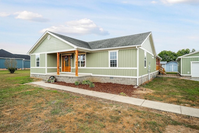 view of front of home with a front yard, covered porch, and a storage shed