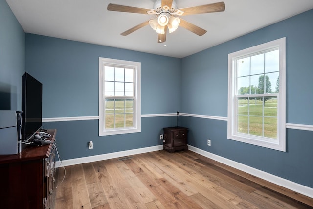 spare room with ceiling fan, light wood-type flooring, and a wealth of natural light