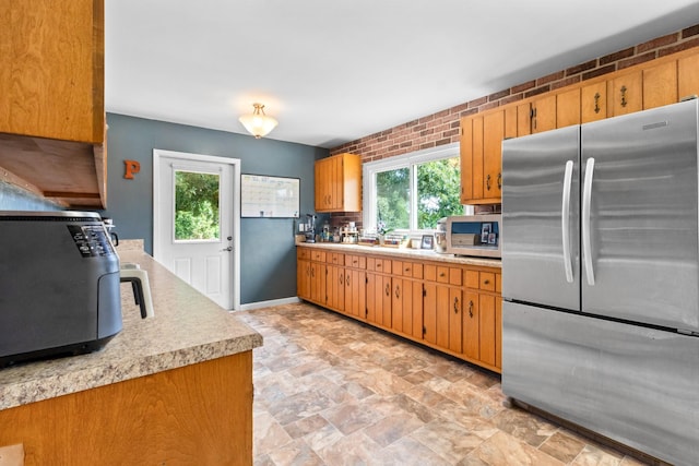 kitchen featuring brick wall, appliances with stainless steel finishes, and a healthy amount of sunlight