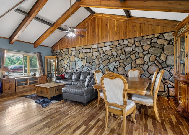 dining space with ceiling fan, wood walls, wood-type flooring, beamed ceiling, and high vaulted ceiling