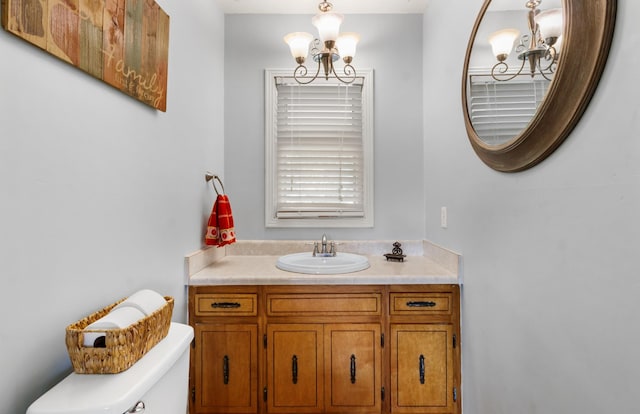 bathroom featuring toilet, a chandelier, and vanity