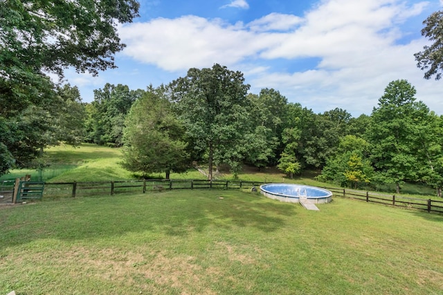 view of yard with a fenced in pool and a rural view