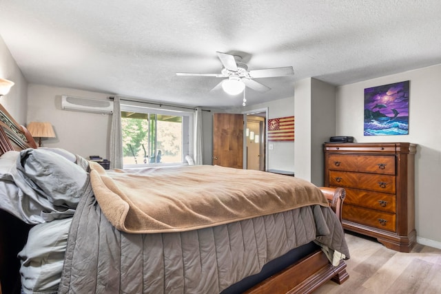 bedroom featuring ceiling fan, light wood-type flooring, a textured ceiling, and a wall mounted air conditioner