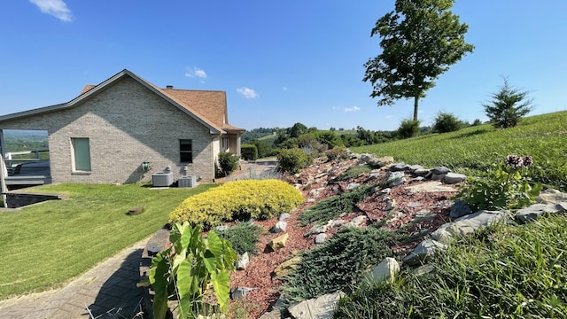 view of home's exterior with cooling unit and a lawn