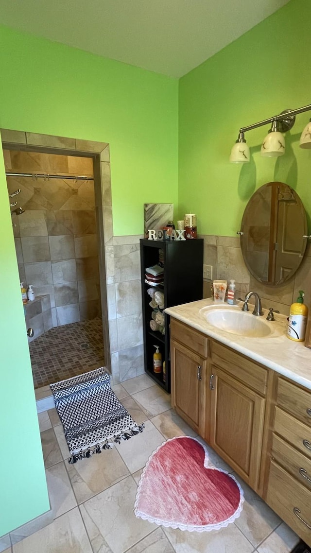 bathroom featuring tile patterned floors, tiled shower, vanity, and tile walls