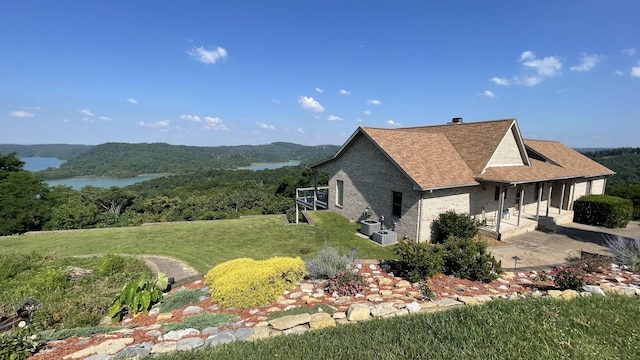 view of home's exterior with a patio, a water view, and a lawn