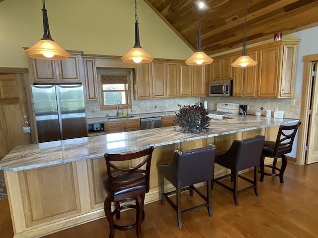 kitchen with a sink, wood finished floors, appliances with stainless steel finishes, wooden ceiling, and light stone countertops