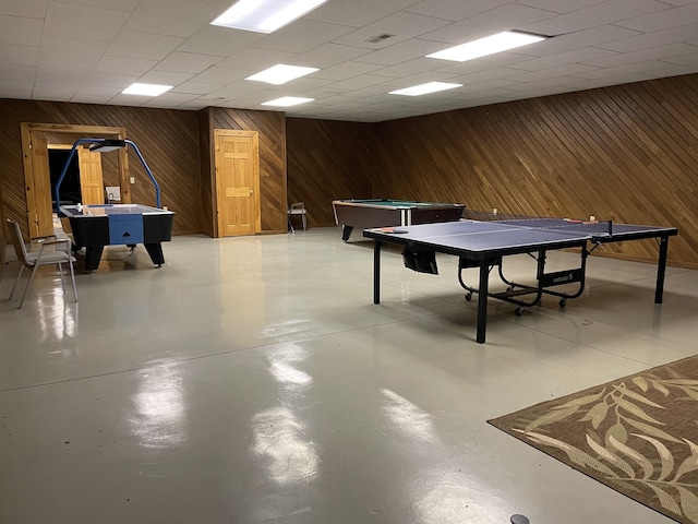 rec room featuring a paneled ceiling, visible vents, wood walls, and finished concrete floors