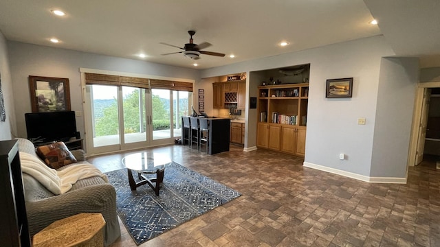 living room featuring recessed lighting, stone finish flooring, baseboards, and a ceiling fan