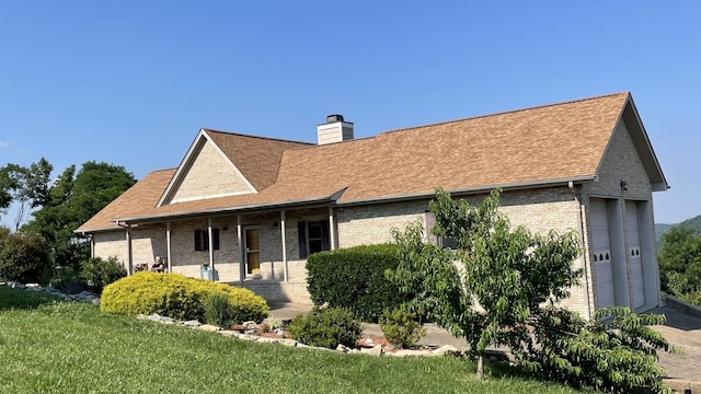 rear view of property with brick siding, a porch, a chimney, and roof with shingles