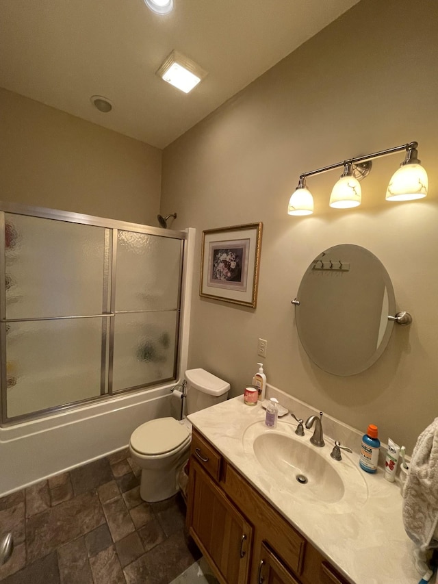 full bathroom with toilet, vanity, stone finish flooring, and bath / shower combo with glass door