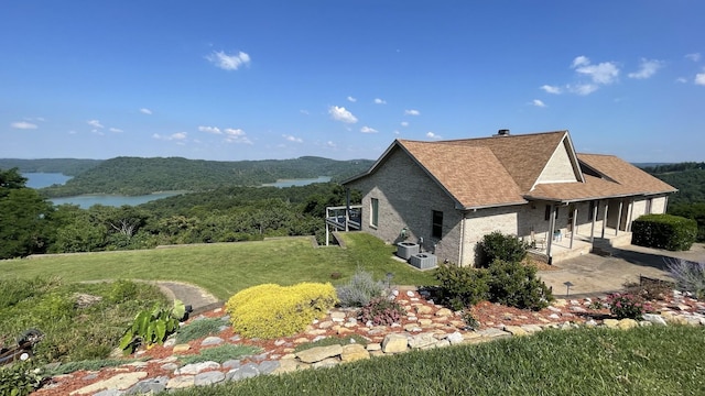 61 Brim Ln, Hilham, TN 38568 - view of side of property featuring a yard, a patio, a forest view, brick siding, and a shingled roof