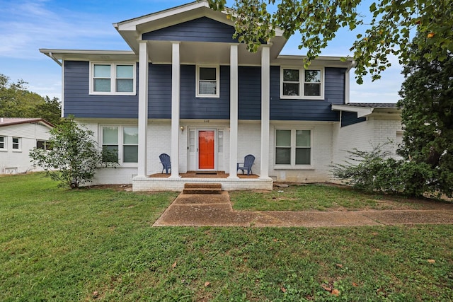 neoclassical / greek revival house featuring a porch, a front lawn, and brick siding