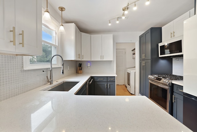 kitchen featuring stainless steel gas range oven, white cabinetry, washer and dryer, decorative light fixtures, and sink