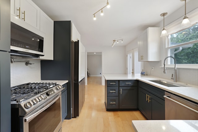 kitchen featuring sink, white cabinetry, stainless steel appliances, pendant lighting, and decorative backsplash