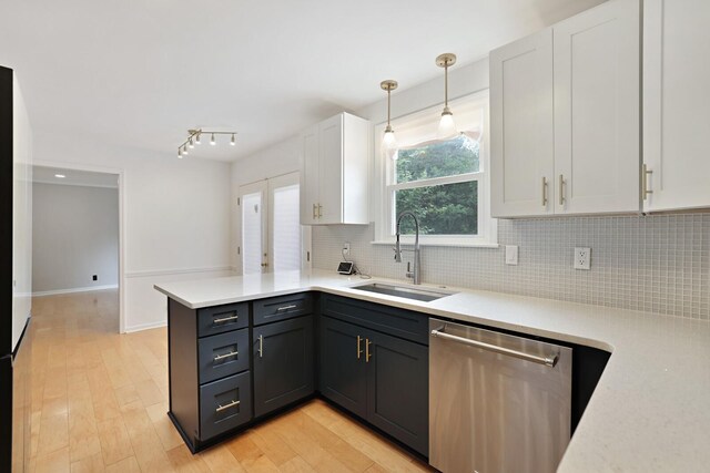 kitchen with a peninsula, a sink, white cabinets, light countertops, and stainless steel dishwasher