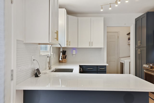 kitchen featuring decorative backsplash, sink, kitchen peninsula, and white cabinets