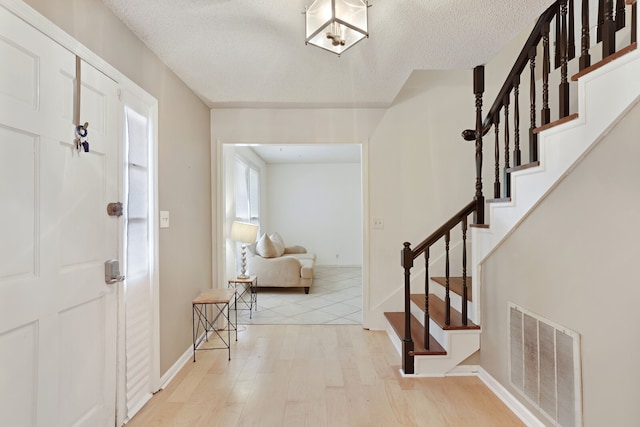 foyer entrance featuring a textured ceiling and light wood-type flooring