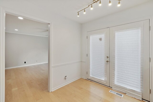 interior space featuring french doors, light wood finished floors, rail lighting, visible vents, and baseboards