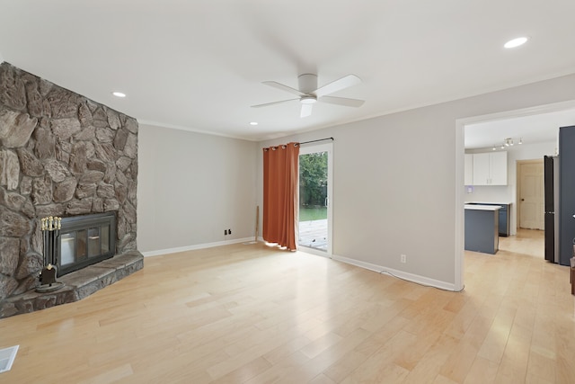 unfurnished living room with crown molding, a fireplace, light wood-type flooring, and ceiling fan