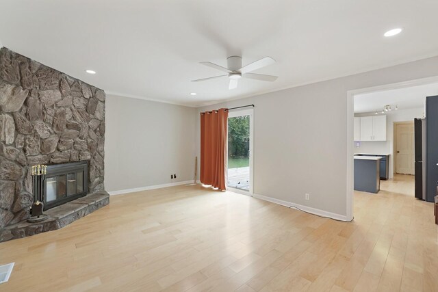 unfurnished living room featuring ceiling fan, a fireplace, light wood-style flooring, and baseboards