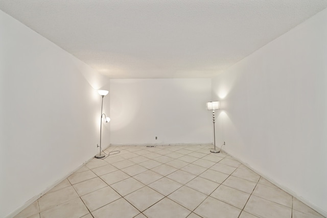 tiled empty room featuring a textured ceiling