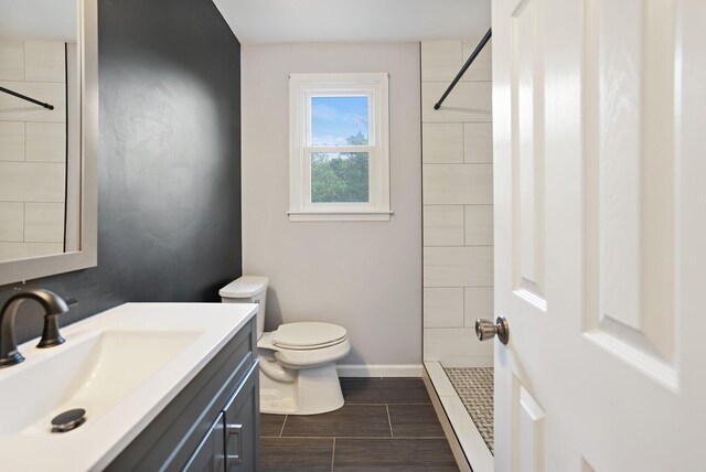 bathroom with vanity, a tile shower, and toilet