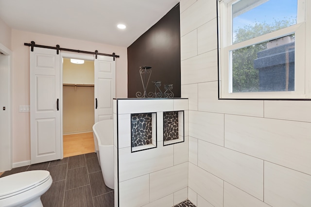 bathroom with toilet, a tub, and wood-type flooring