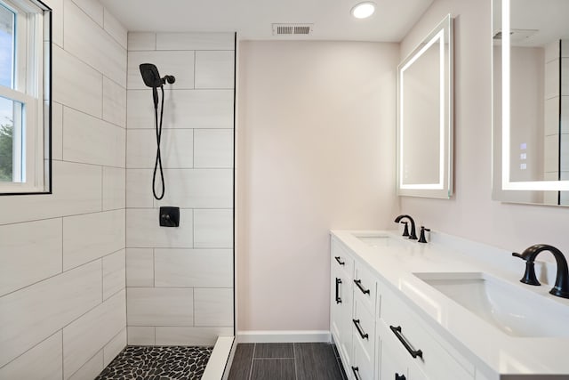 bathroom with vanity and a tile shower