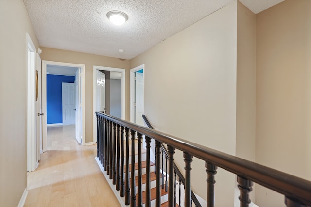 hall featuring light hardwood / wood-style flooring and a textured ceiling