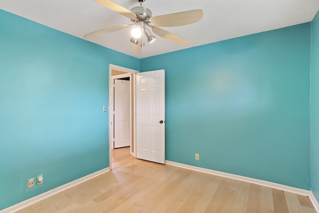 spare room with a textured ceiling, light wood-type flooring, and ceiling fan