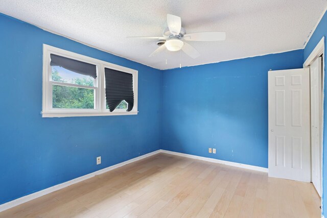 unfurnished room with a textured ceiling, wood finished floors, a ceiling fan, and baseboards