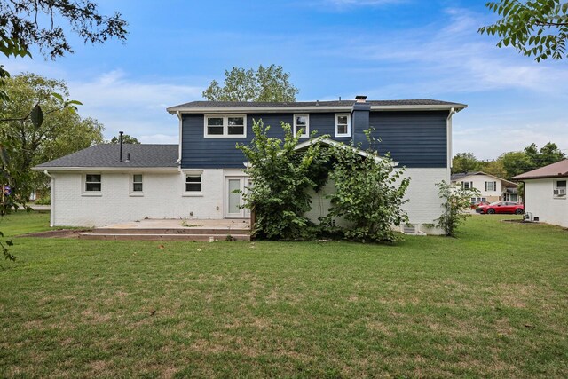 rear view of house with brick siding, a lawn, and a wooden deck