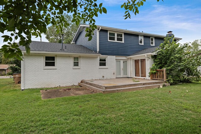 rear view of house featuring brick siding, a lawn, a chimney, and a wooden deck