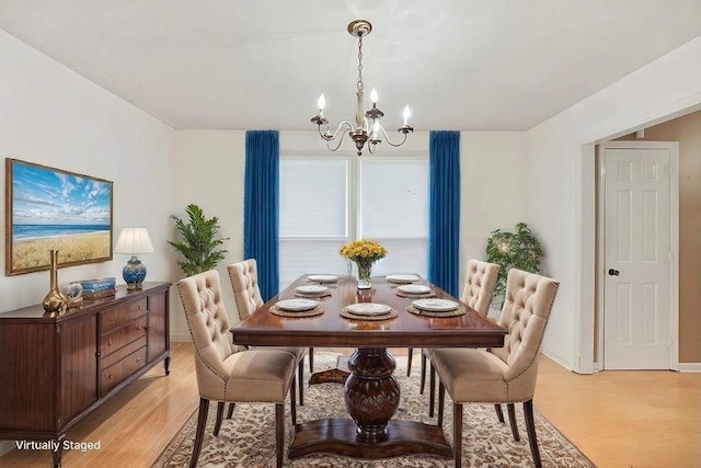 dining area featuring a chandelier, baseboards, and light wood finished floors