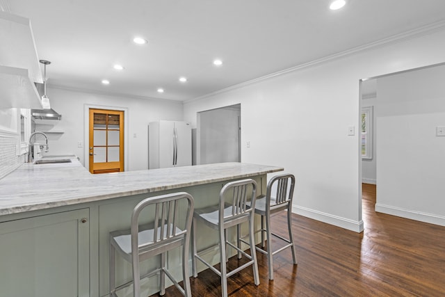 kitchen with a breakfast bar, sink, white fridge, kitchen peninsula, and dark wood-type flooring