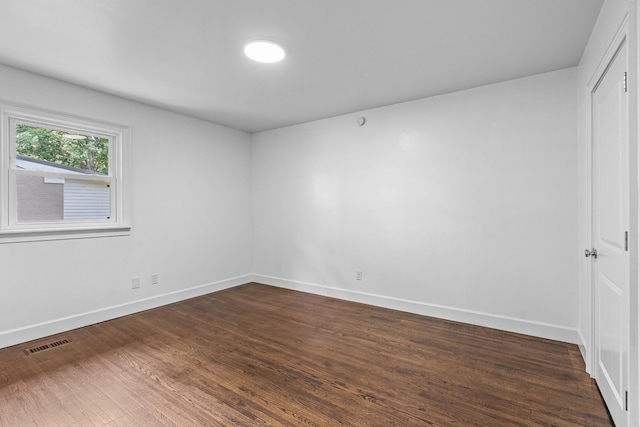 unfurnished room with baseboards, visible vents, and dark wood finished floors