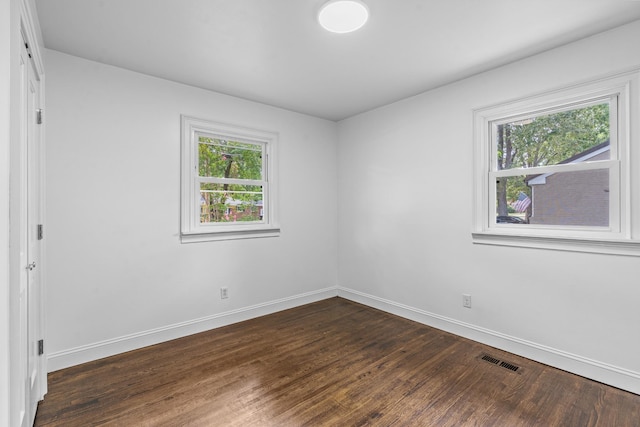 spare room featuring baseboards, visible vents, and dark wood-style flooring