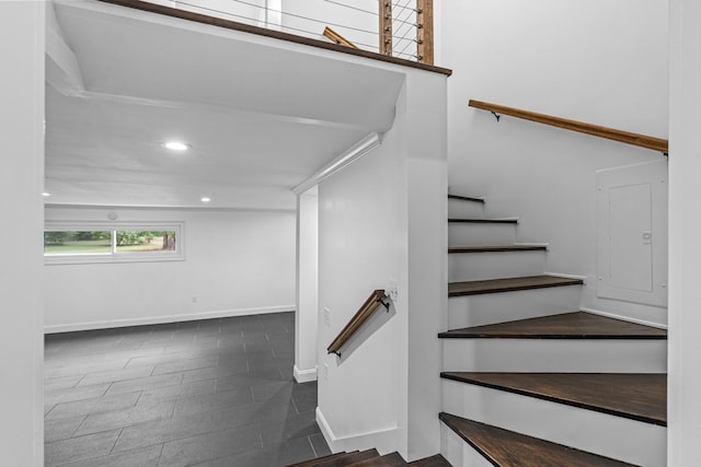 staircase featuring electric panel, baseboards, and recessed lighting