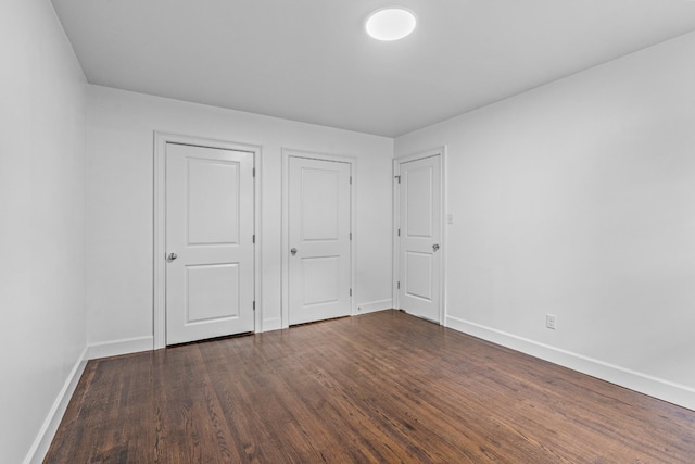 unfurnished bedroom with dark wood-style flooring and baseboards