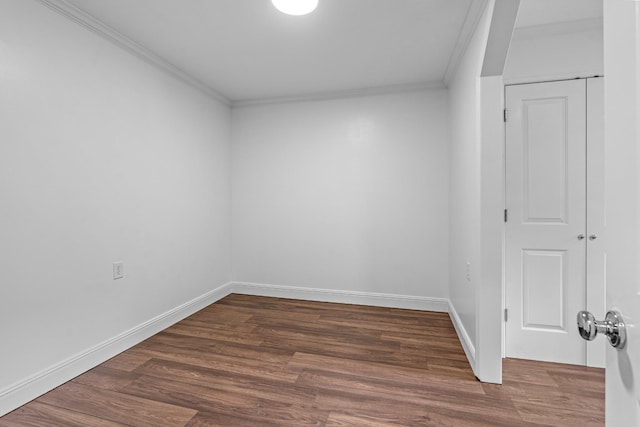 spare room featuring dark wood-style floors, crown molding, and baseboards