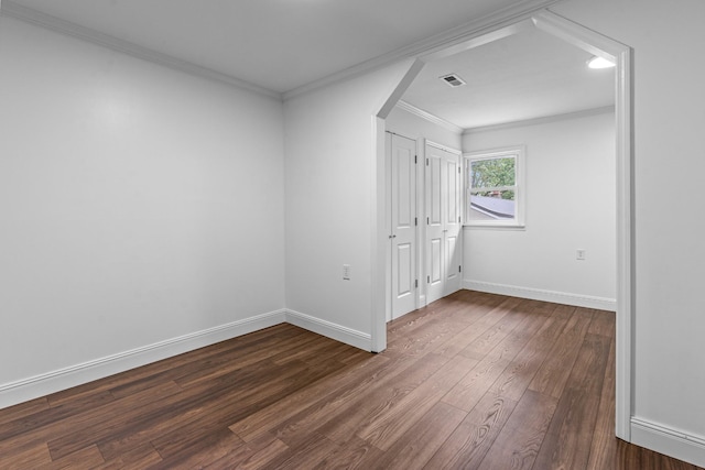 unfurnished room featuring baseboards, arched walkways, visible vents, dark wood finished floors, and crown molding