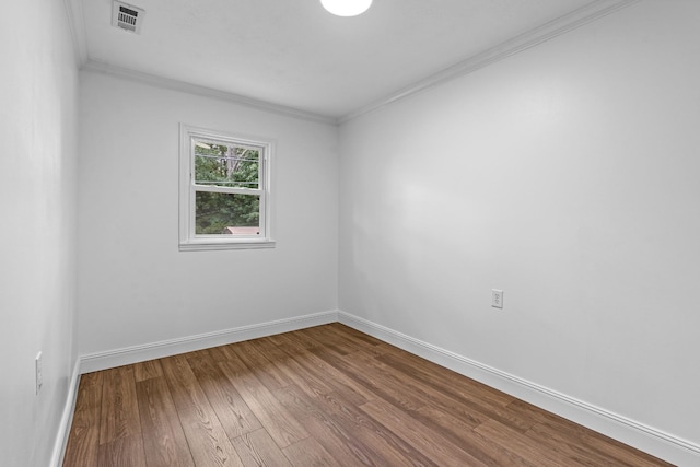 unfurnished room with visible vents, crown molding, baseboards, and wood finished floors