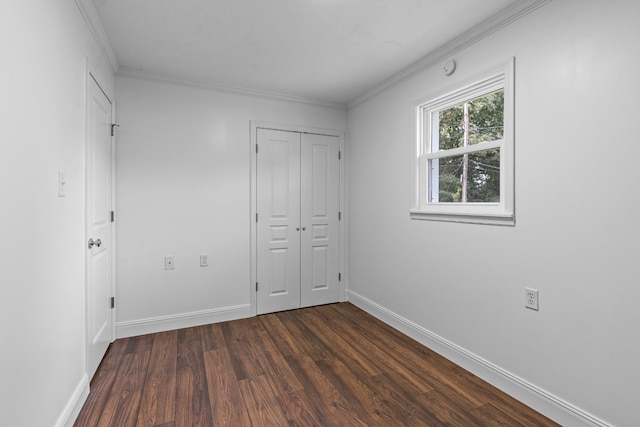 unfurnished bedroom featuring crown molding, dark wood-style flooring, a closet, and baseboards