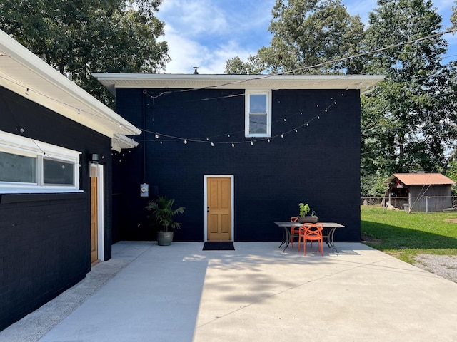 rear view of property featuring a patio area, brick siding, fence, and outdoor dining area