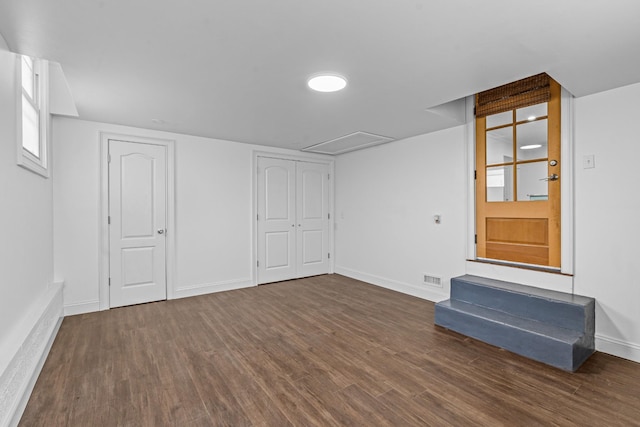 below grade area featuring dark wood-style floors, visible vents, and baseboards