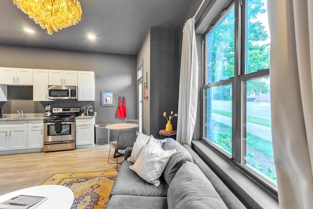 living room featuring light wood-type flooring, sink, and an inviting chandelier