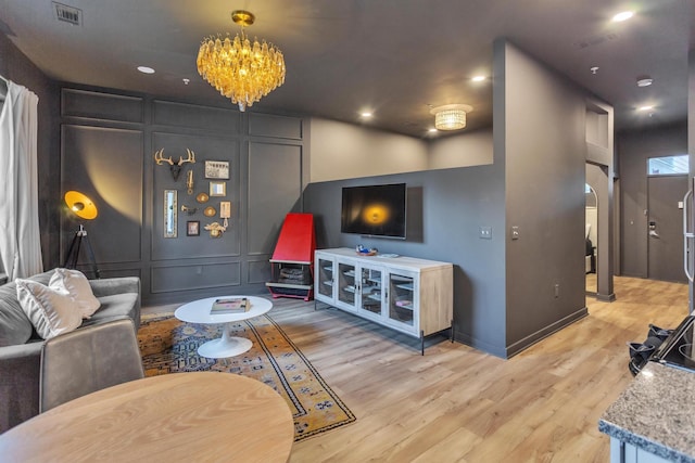 living room with light wood-type flooring and an inviting chandelier