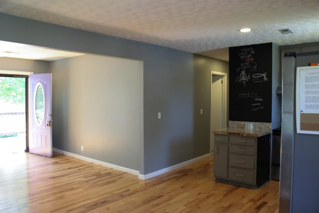 interior space with baseboards, light stone countertops, gray cabinets, a textured ceiling, and light wood-type flooring