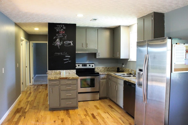 kitchen featuring under cabinet range hood, stainless steel appliances, a sink, and gray cabinetry